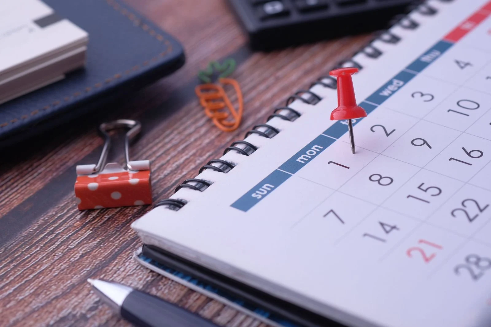 Escritorio con calendario, chinchetas y material de planificación dispuestos para organizar una agenda.