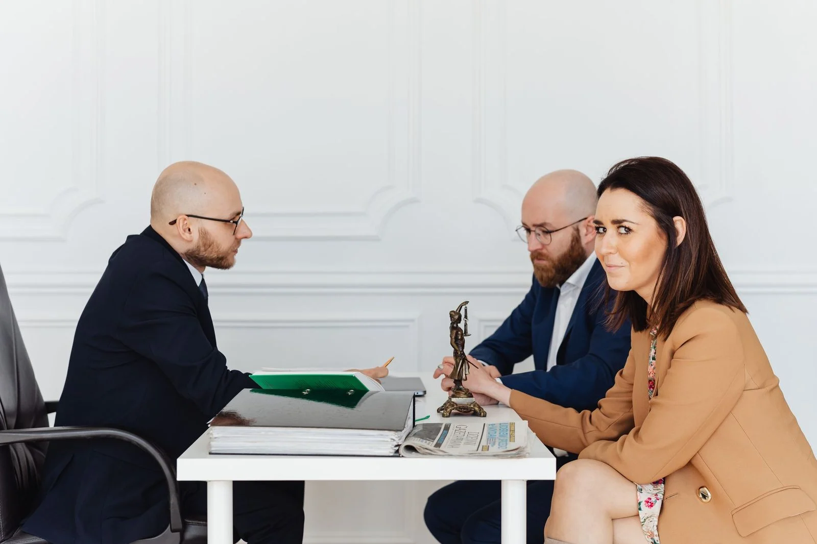 A lawyer meets with a couple across a desk in an elegant office to discuss their immigration case.