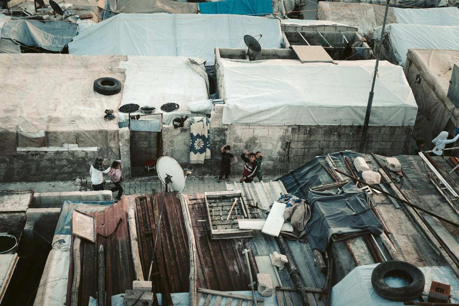 Aerial view of densely packed rooftops and shelters in a Syrian refugee camp.