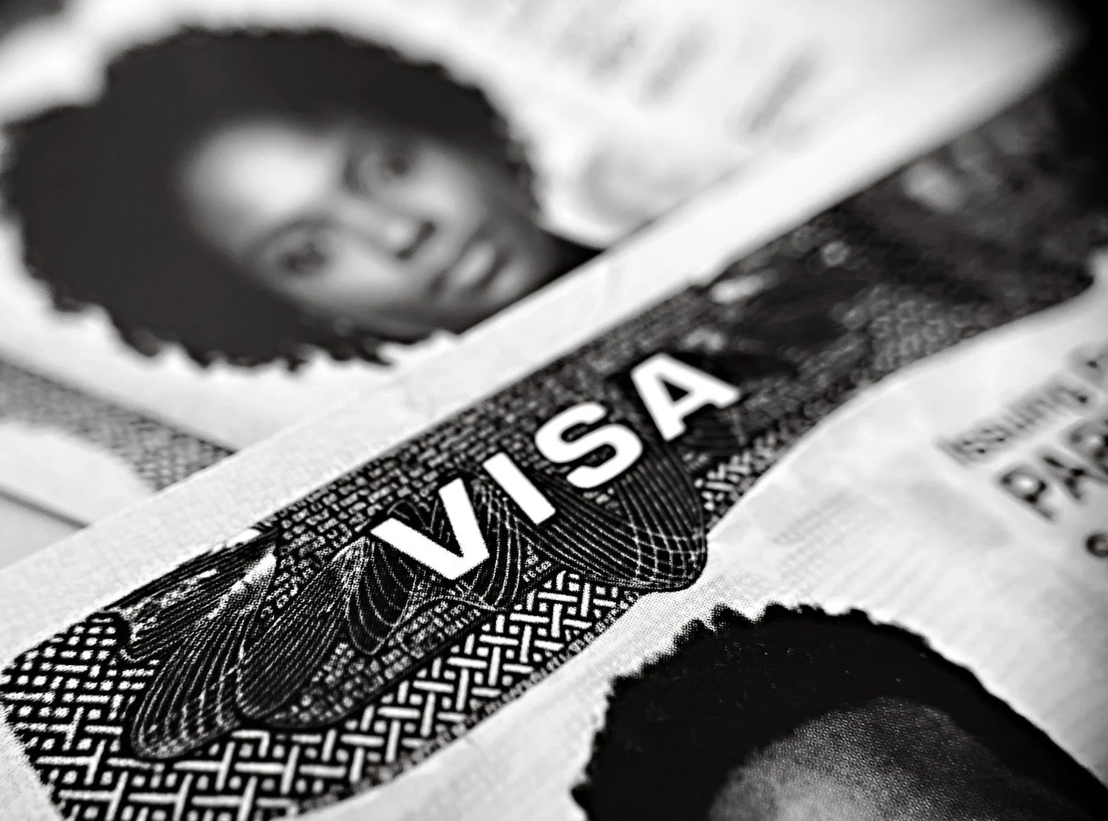 Black-and-white close-up of a visa document showing a partial portrait photo and printed visa text.