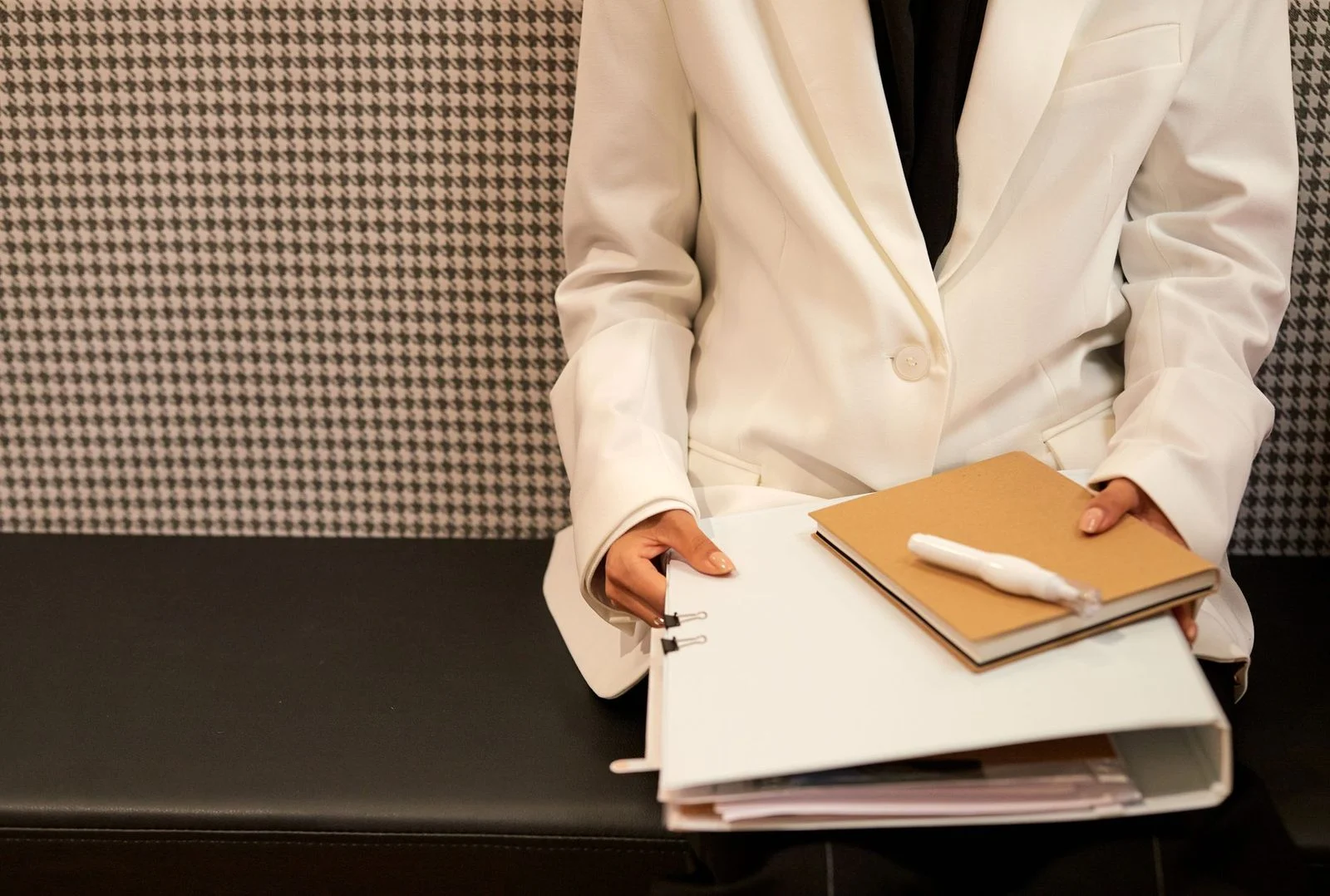 Profesional de negocios con traje blanco sosteniendo documentos en una oficina moderna.