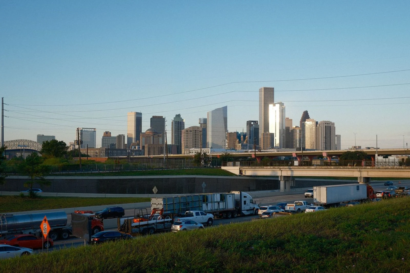 Houston skyline at sunset with busy highway traffic in the foreground.