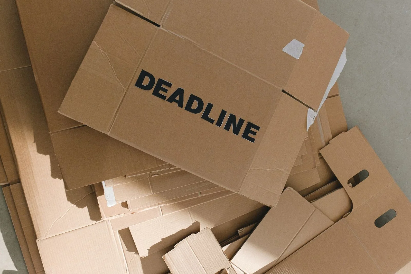 Stacked cardboard boxes in an empty room, with a bold "Deadline" label drawing attention to urgency.