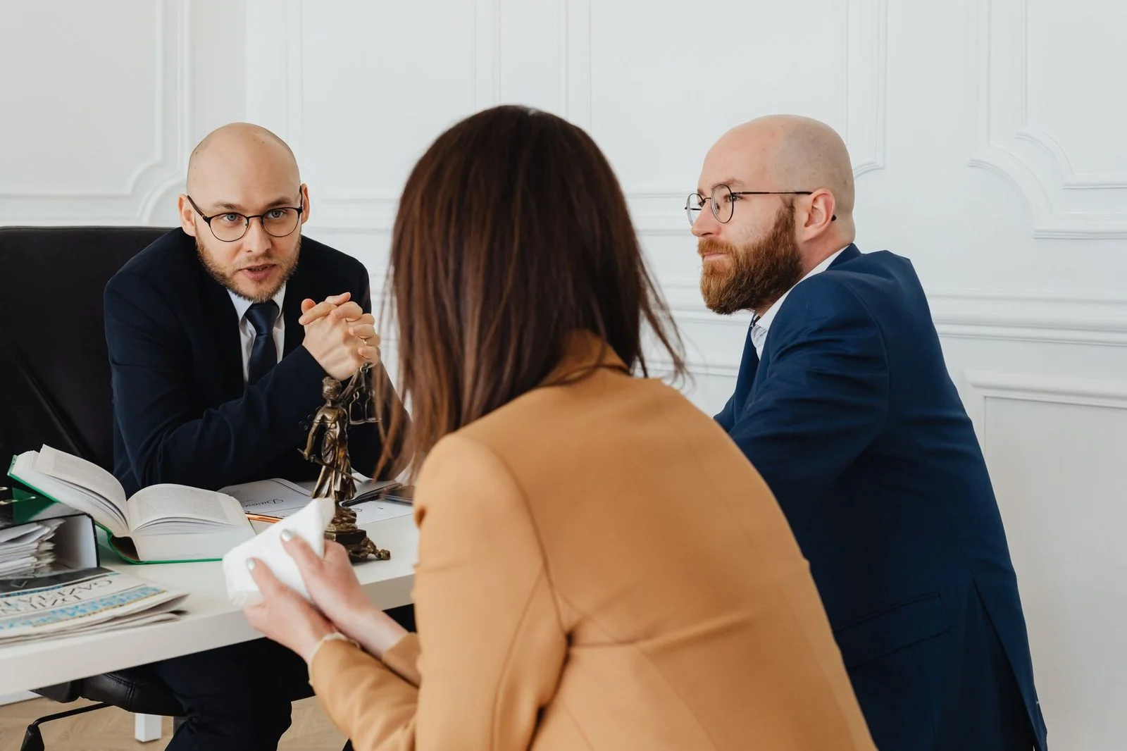 Two lawyers sit across from each other at a desk in a modern office, reviewing legal documents together.