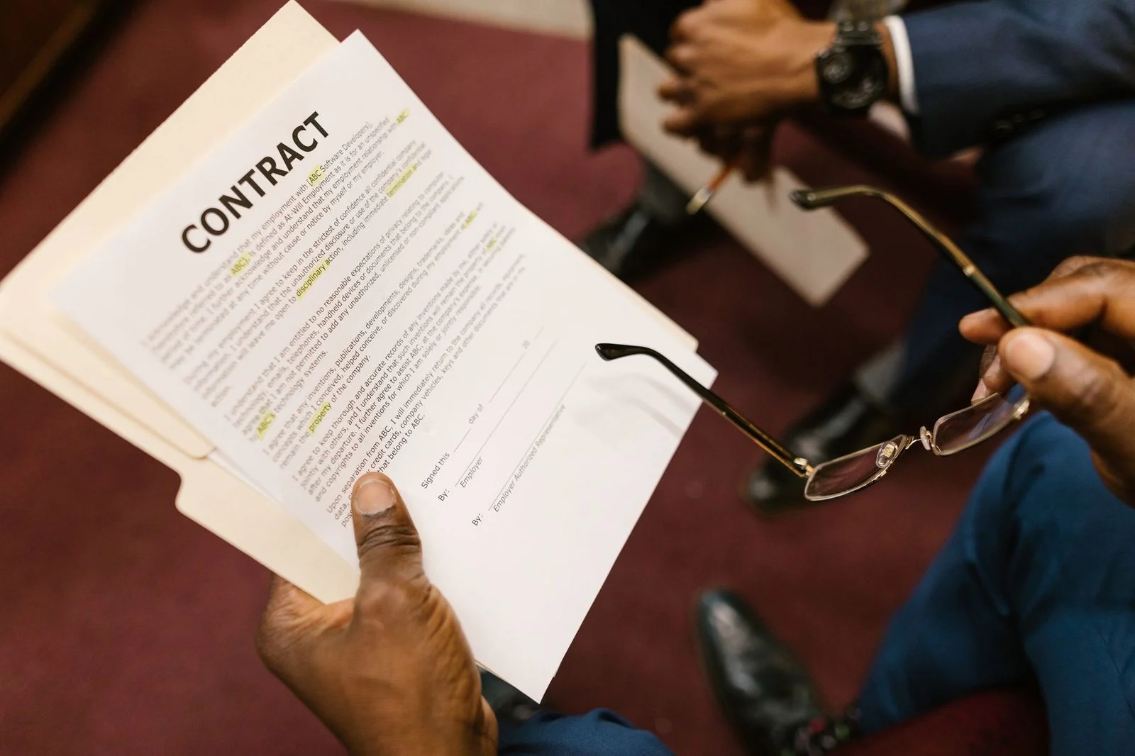 Dos personas revisan juntas un contrato impreso sobre un escritorio, con las manos apoyadas en el documento.