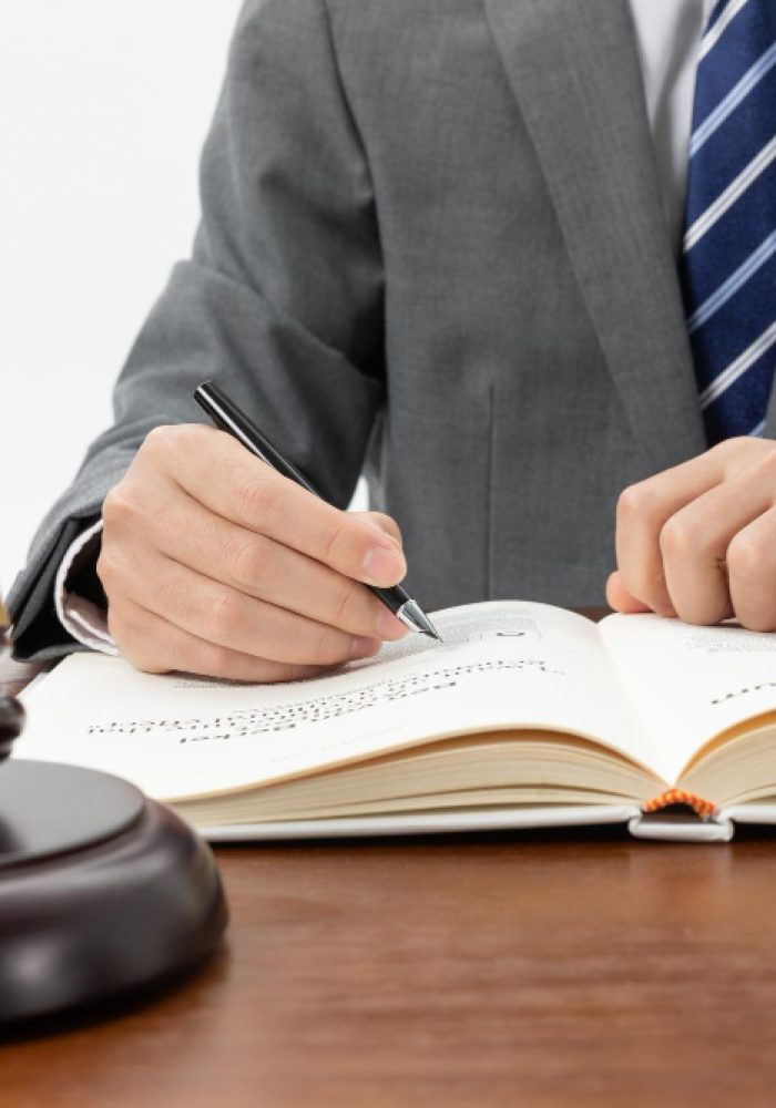 closeup-shot-person-writing-book-with-gavel-table